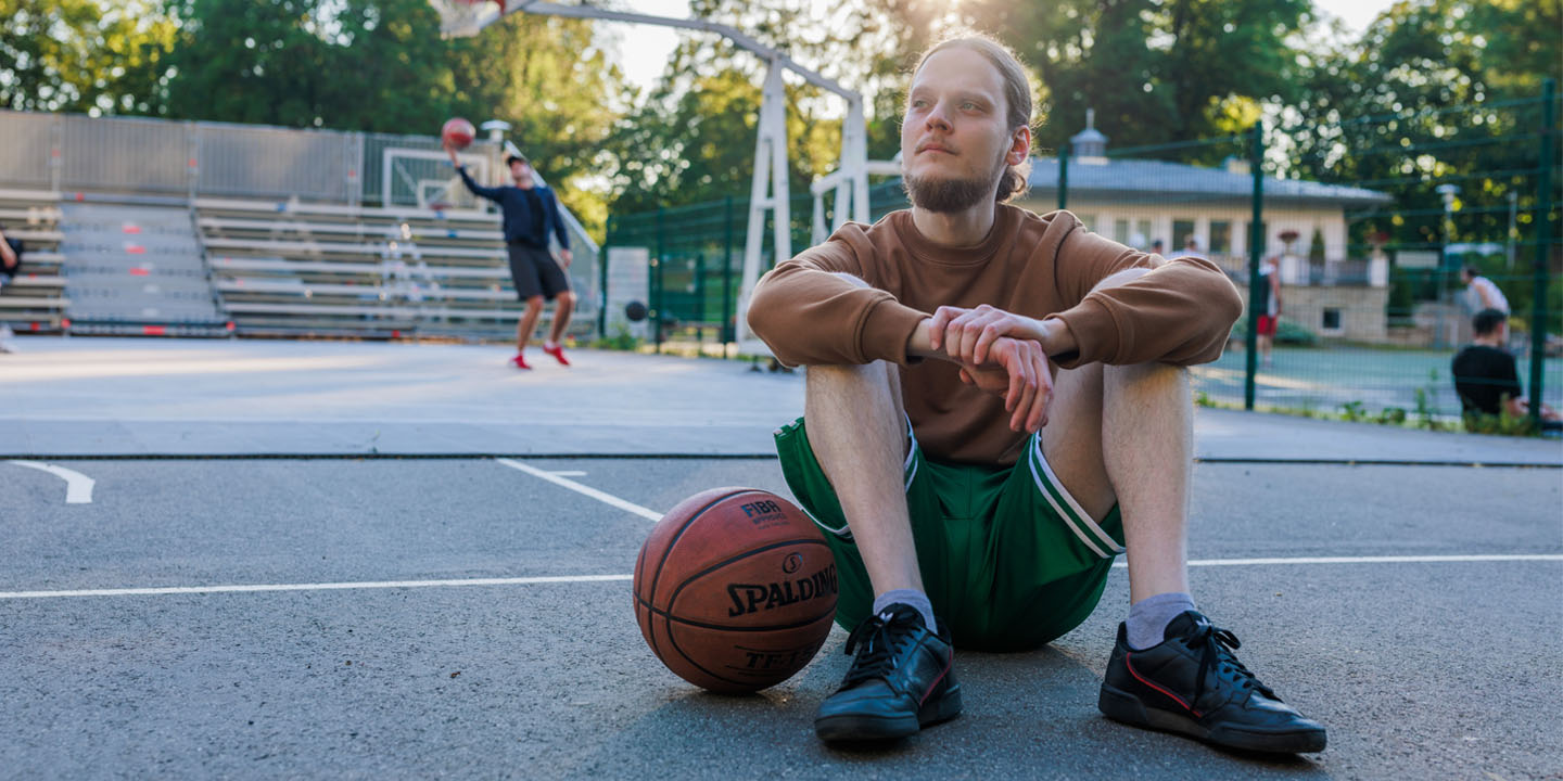 man sitting outdoors. basketball court.